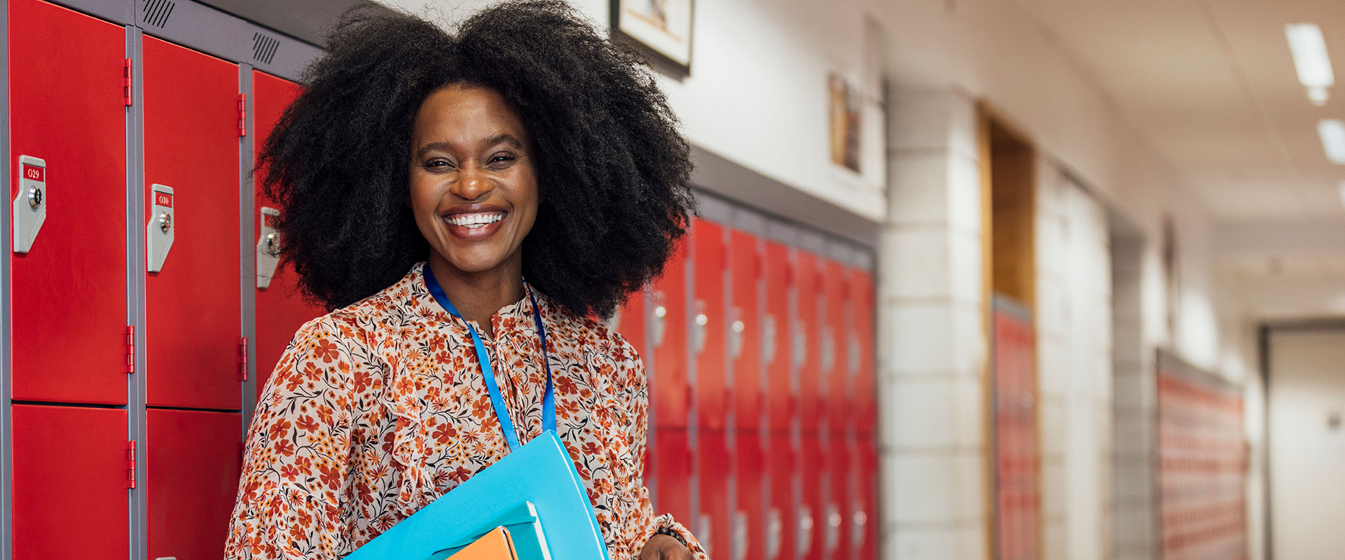 Woman administrator in school hallway leaning against lockers