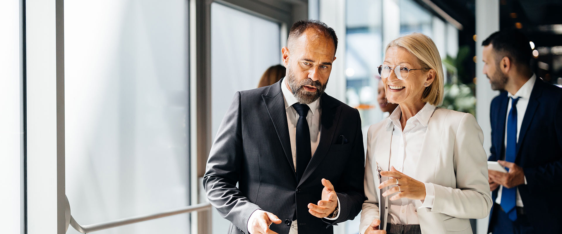 Two business professionals are having a conversation while walking in a modern office environment