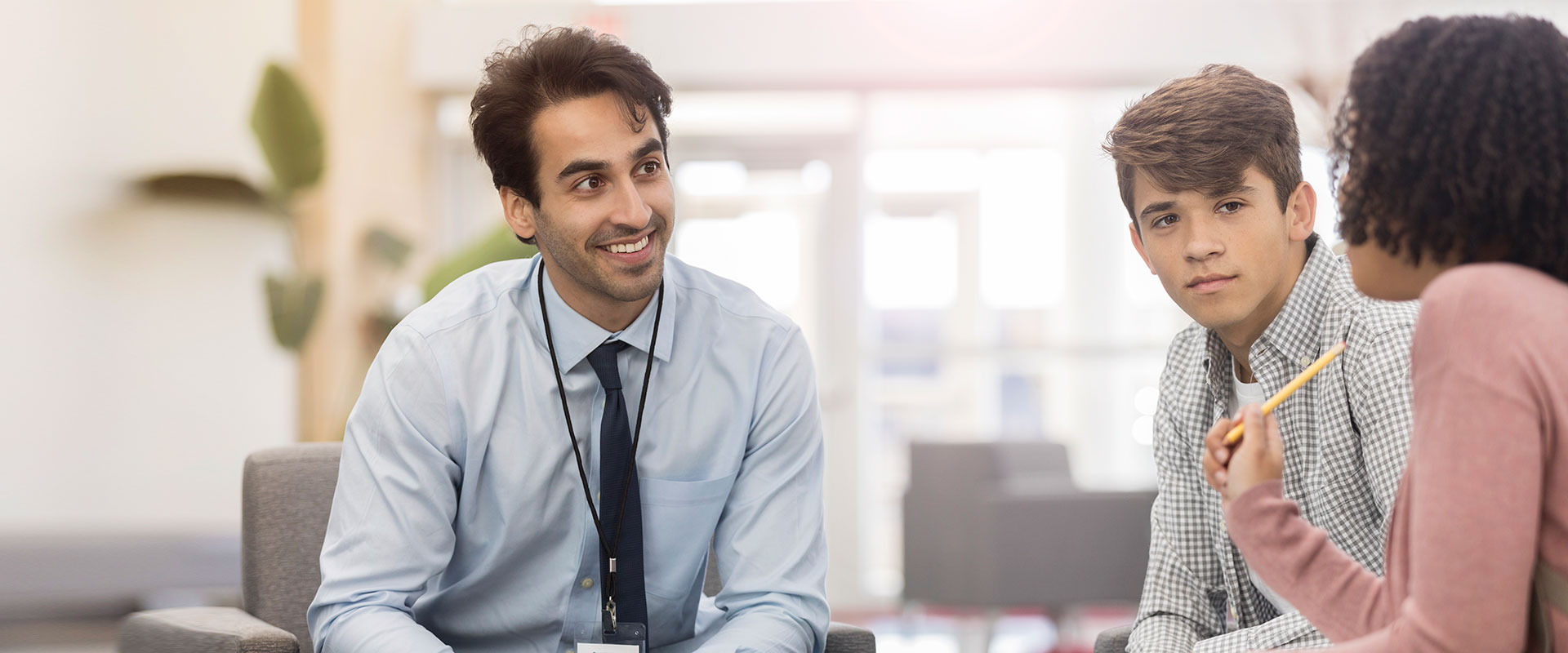 Teacher and counselor taking to teen student in teachers office